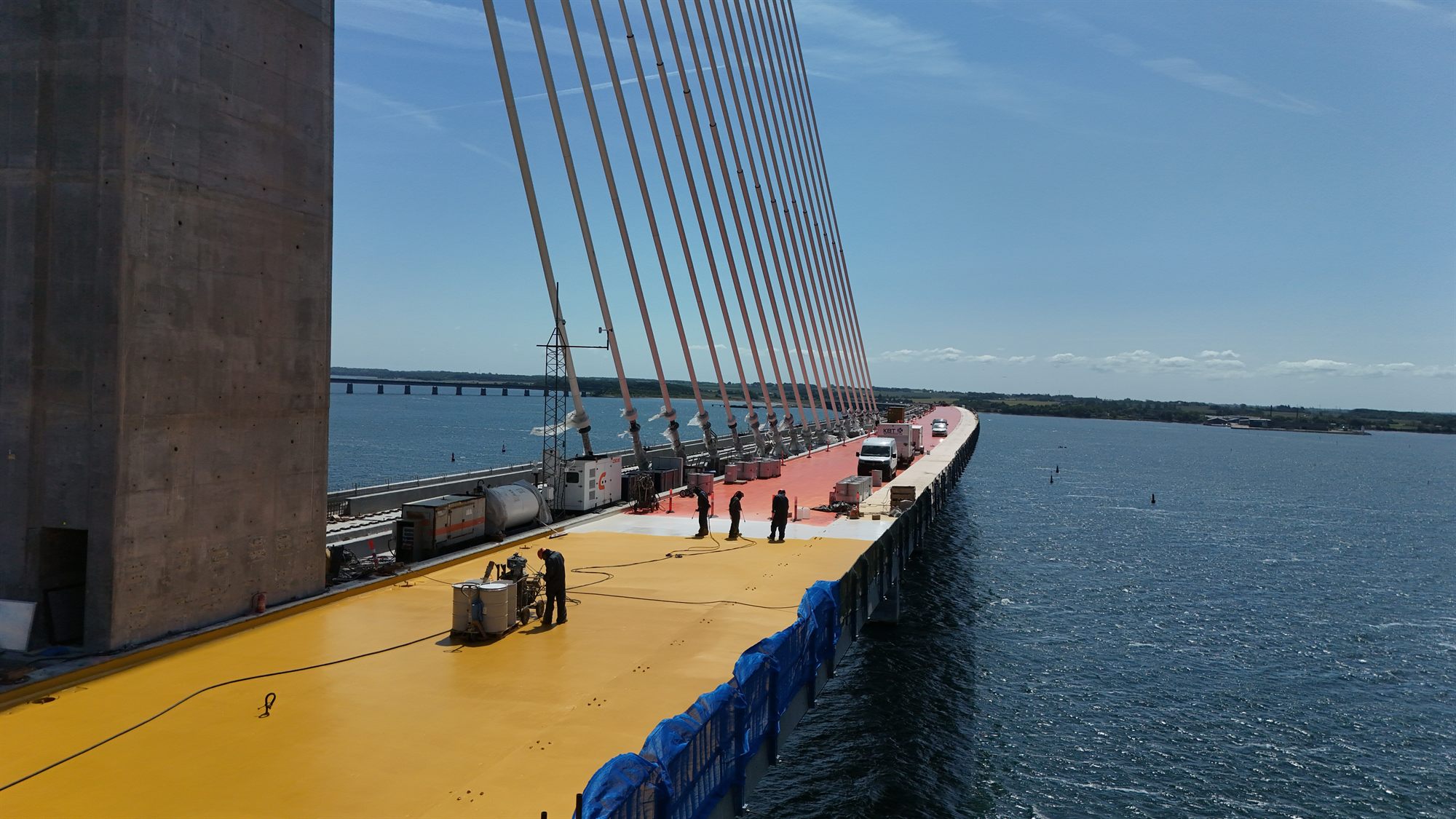 Luftfoto af Storstrømsbroen med gul KBT Type 5 bromembran påført brodækket langs jernbanesporene over vandet