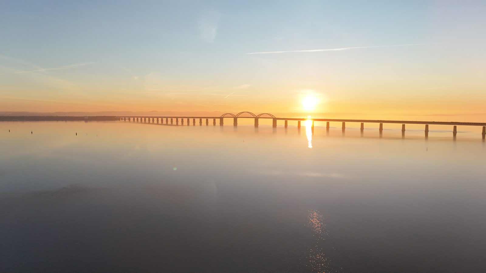 The Storstrøm Bridge (Queen Margrethe II's Bridge) at sunrise, seen from a drone over Storstrømmen
