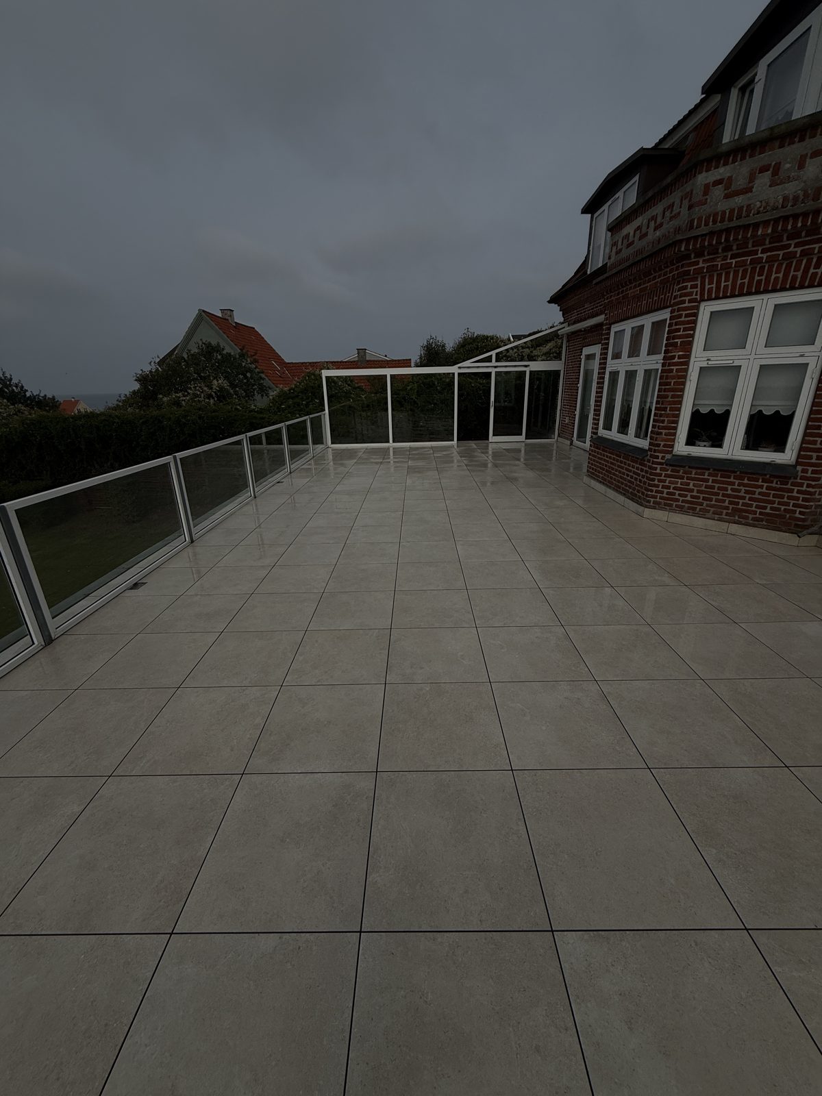 Den færdige terrasse med klinker på fødder, glasværn og facade